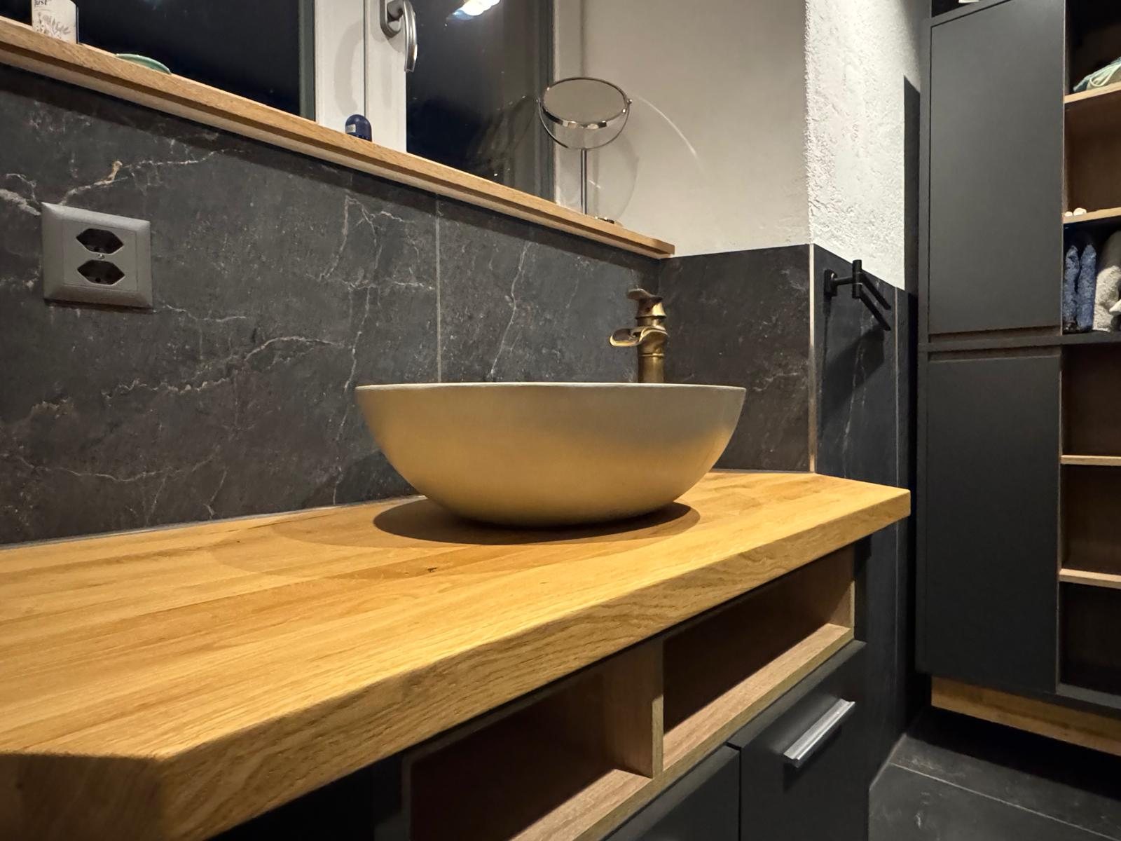Fertiges Badezimmer mit dunkler Keramik und Holzdetails