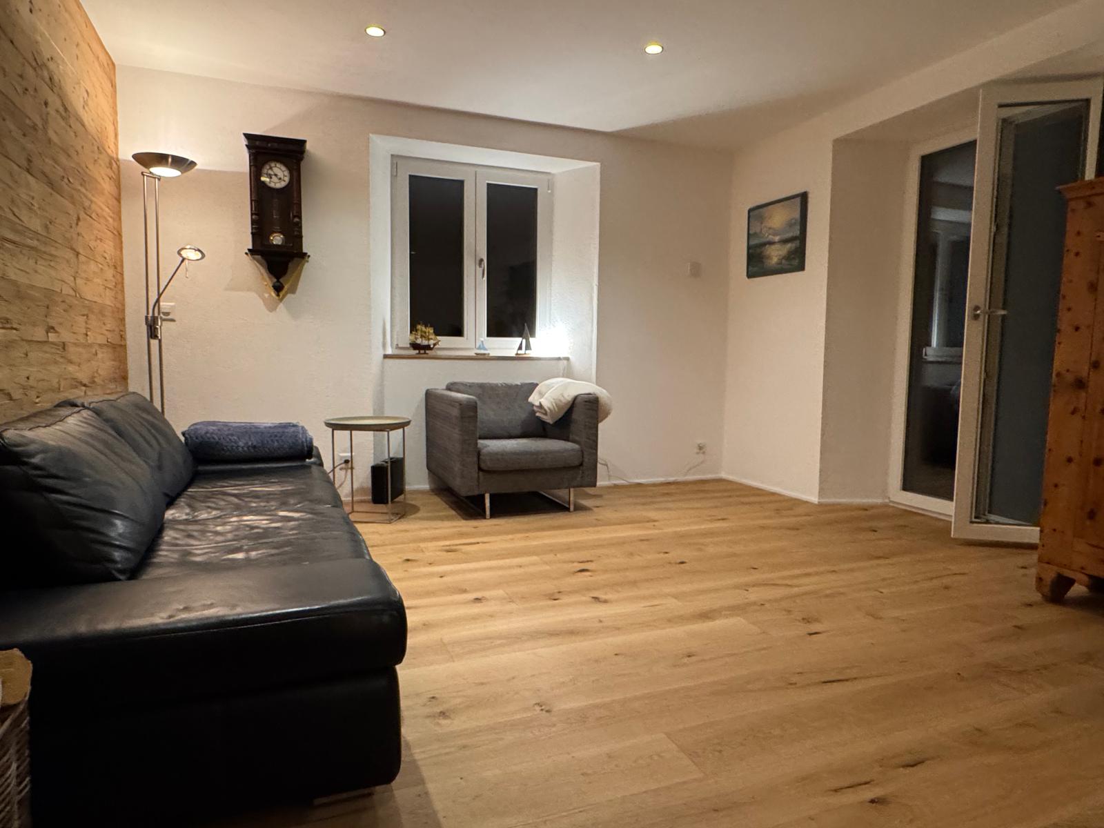 Fertiges Wohnzimmer mit Sofa, Sessel und Holzboden