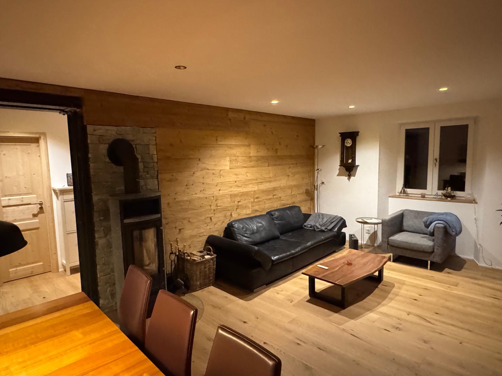 Fertiges Wohnzimmer mit Holzboden, Holzverkleidung und Ofen